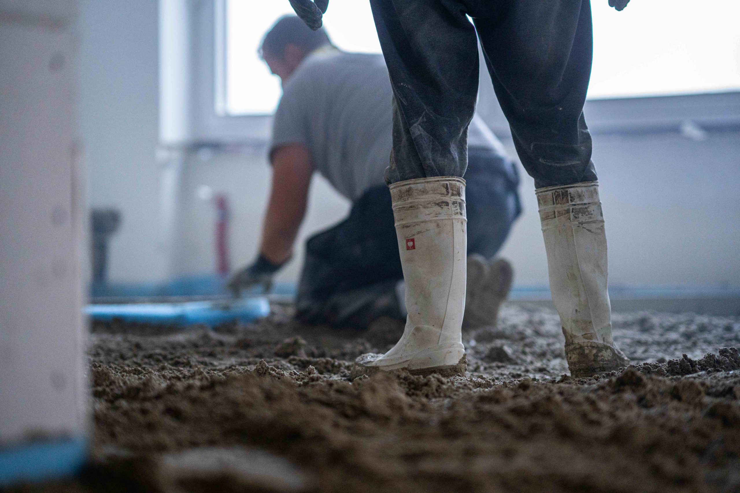 Mitarbeiter beim Verteilen von frischem Estrich im Innenraum