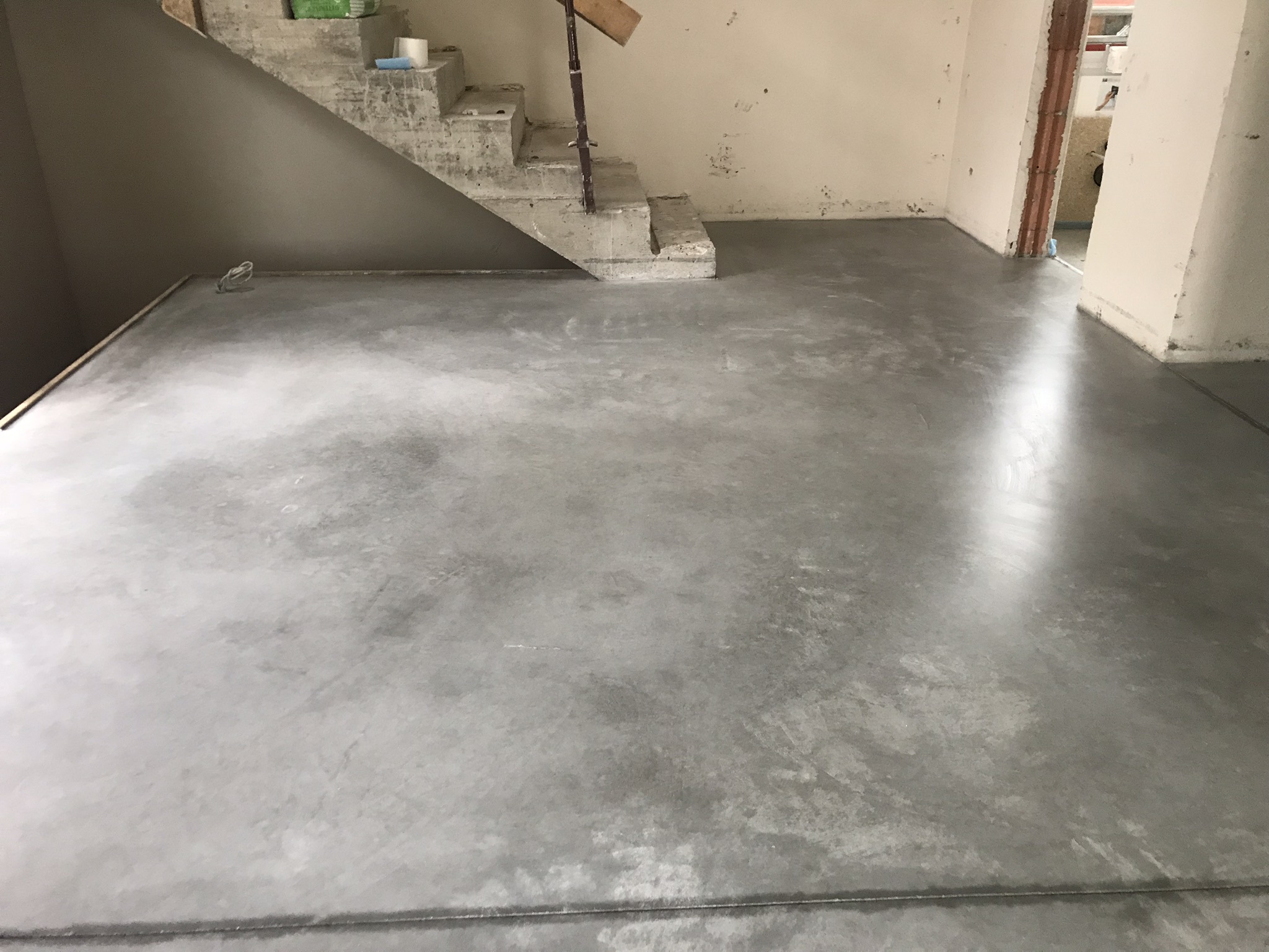 Geglättete Estrichfläche in einem Rohbauraum mit Treppe