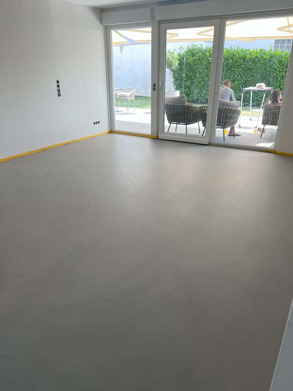 Fertige graue Bodenfläche in einem Wohnraum mit Terrassentür