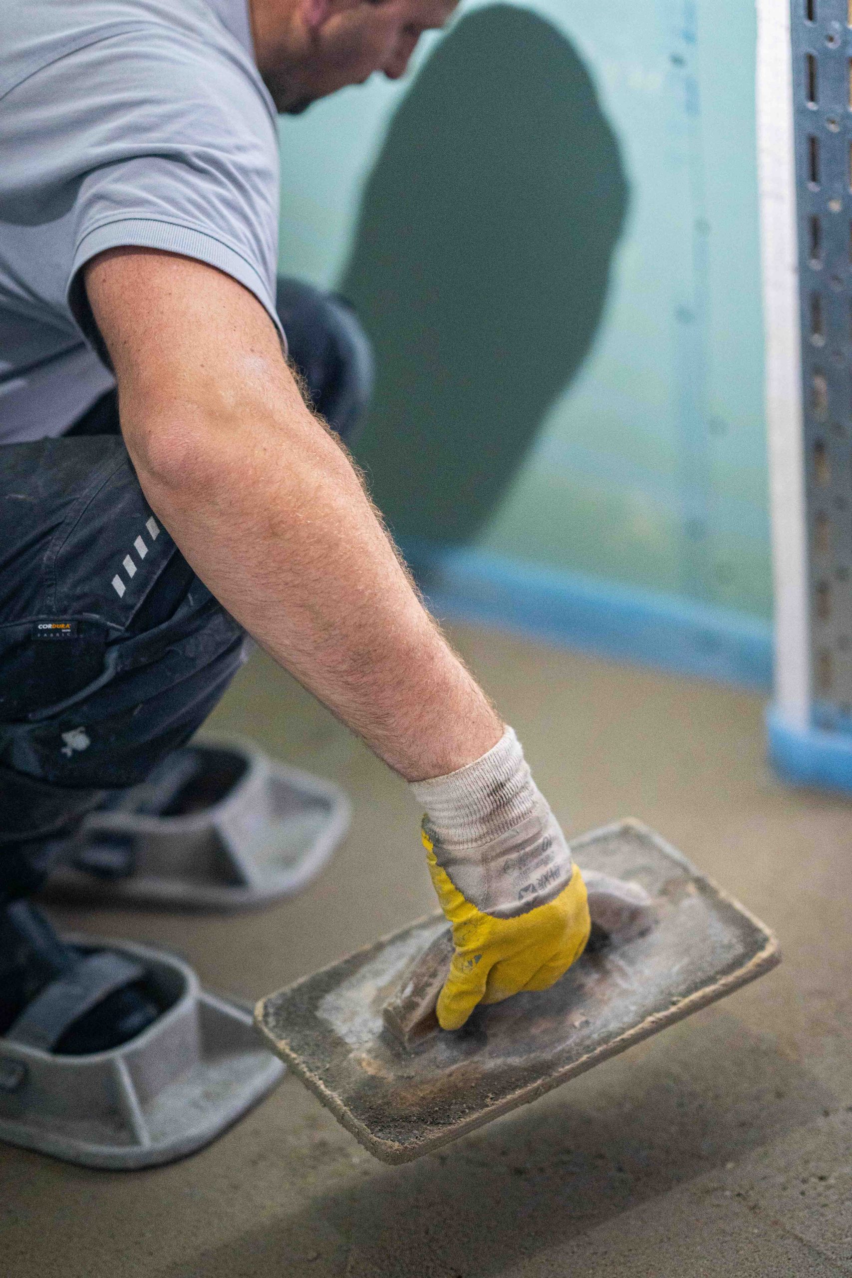 Mitarbeiter glättet eine Estrichfläche mit dem Handglätter