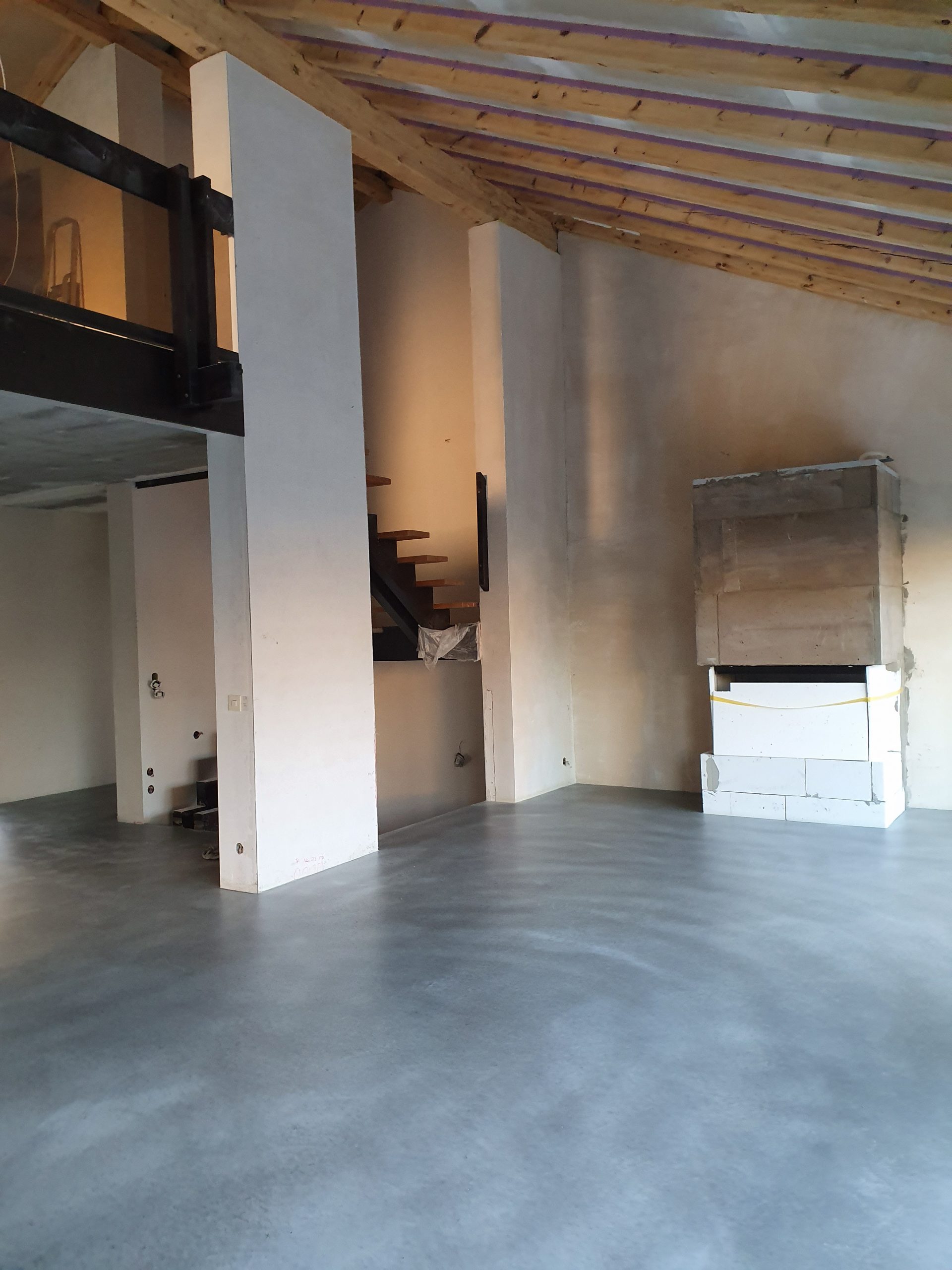 Sichtestrichboden in einem Raum mit Holzdachkonstruktion